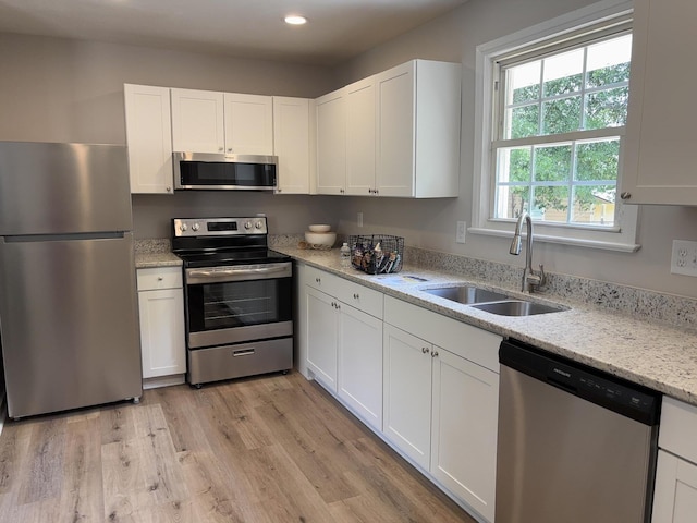 2438 Ridge Rd, Augusta, GA 30906 - kitchen featuring a sink, light stone counters, light wood finished floors, stainless steel appliances, and white cabinetry