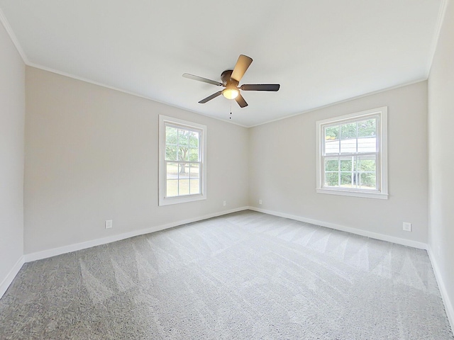 carpeted empty room with a wealth of natural light, crown molding, and ceiling fan