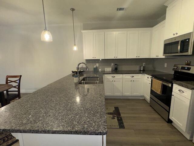 kitchen with white cabinets, sink, stainless steel appliances, and dark stone counters