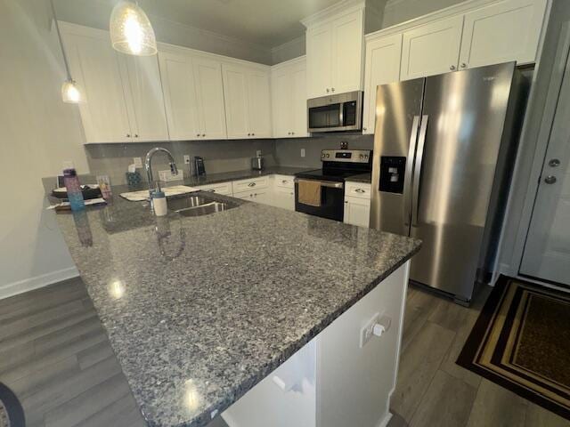 kitchen with appliances with stainless steel finishes, sink, dark stone countertops, white cabinetry, and hanging light fixtures