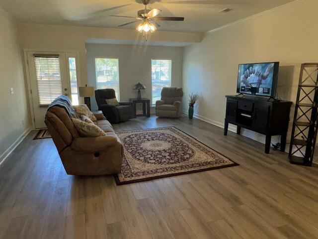 living room featuring ceiling fan, crown molding, and wood-type flooring