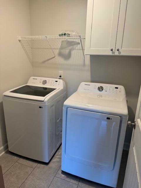 laundry room with cabinets, washer and clothes dryer, and light tile patterned flooring