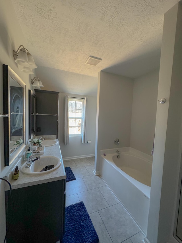 bathroom with a tub to relax in, tile patterned flooring, vanity, and a textured ceiling