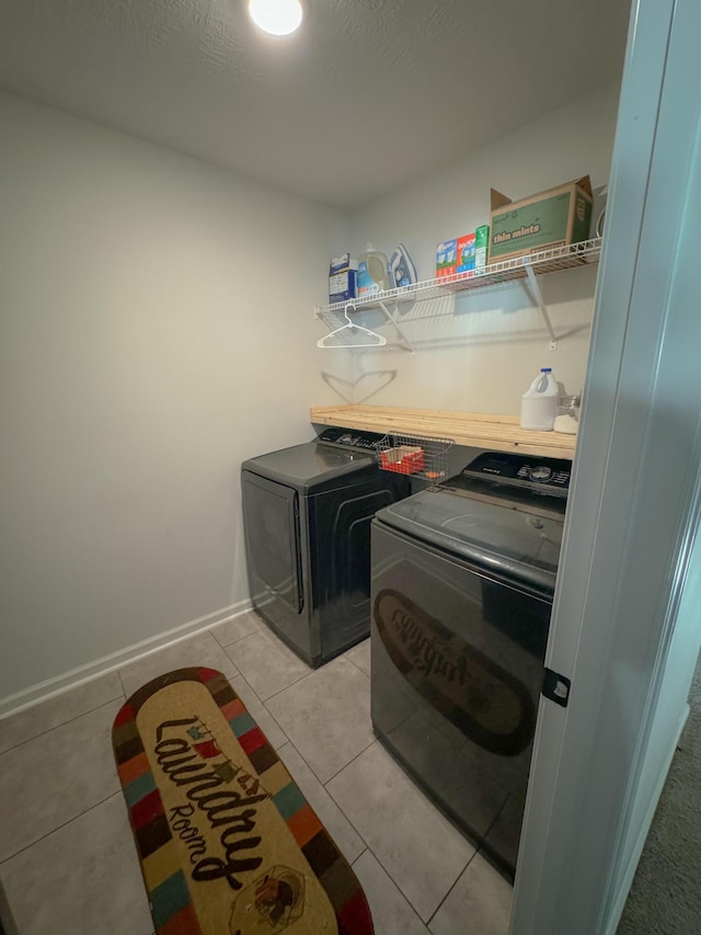 laundry area with independent washer and dryer and light tile patterned floors