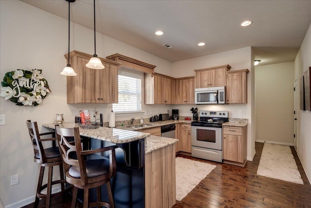 kitchen featuring pendant lighting, appliances with stainless steel finishes, light stone counters, kitchen peninsula, and a breakfast bar area