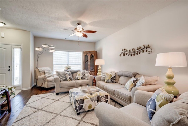 living room featuring a textured ceiling, ceiling fan, and dark wood-type flooring