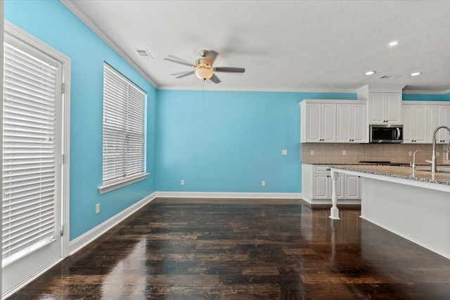 1717 Ethan Way, Hephzibah, GA 30815 - kitchen featuring stainless steel microwave, ceiling fan, backsplash, crown molding, and white cabinets