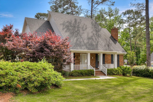 cape cod-style house with roof with shingles, a chimney, a porch, and a front yard