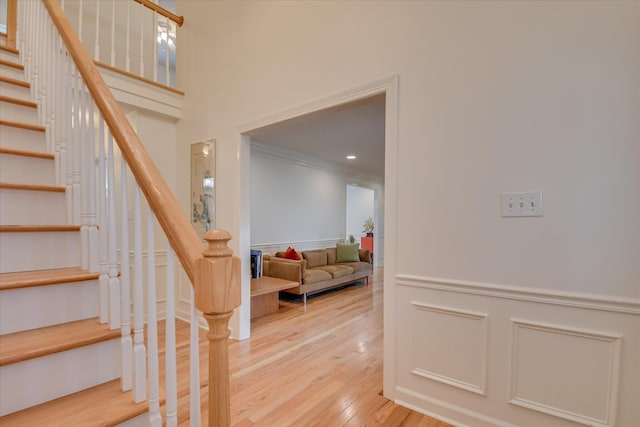 stairs featuring recessed lighting, wood finished floors, a wainscoted wall, and ornamental molding