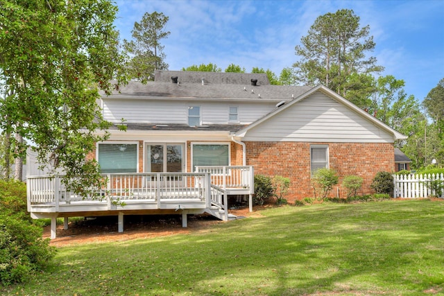 rear view of property featuring fence, a deck, a yard, and brick siding