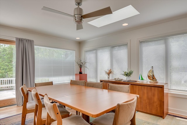 dining space featuring crown molding, light wood-style flooring, recessed lighting, a ceiling fan, and a skylight