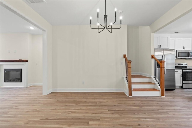 1227 Miller St, Augusta, GA 30901 - unfurnished dining area featuring light wood-style flooring, a chandelier, baseboards, a glass covered fireplace, and recessed lighting