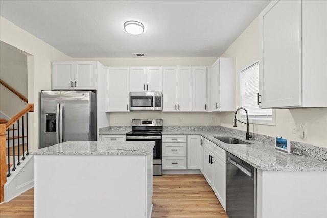 1227 Miller St, Augusta, GA 30901 - kitchen with stainless steel appliances, a sink, light wood-style flooring, a kitchen island, and light stone counters