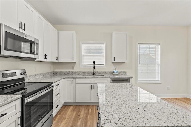 1227 Miller St, Augusta, GA 30901 - kitchen with stainless steel appliances, a sink, light wood-style flooring, white cabinetry, and plenty of natural light