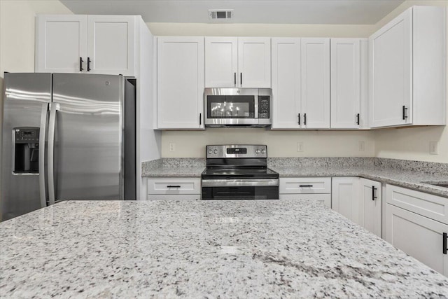 1227 Miller St, Augusta, GA 30901 - kitchen featuring stainless steel appliances, light stone counters, and white cabinetry