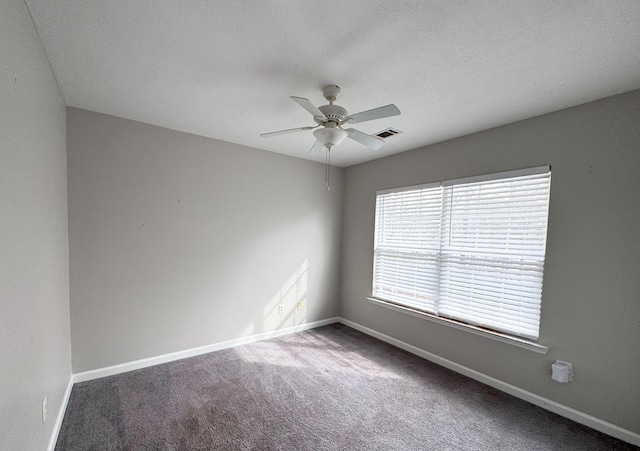 carpeted empty room with visible vents, baseboards, and ceiling fan