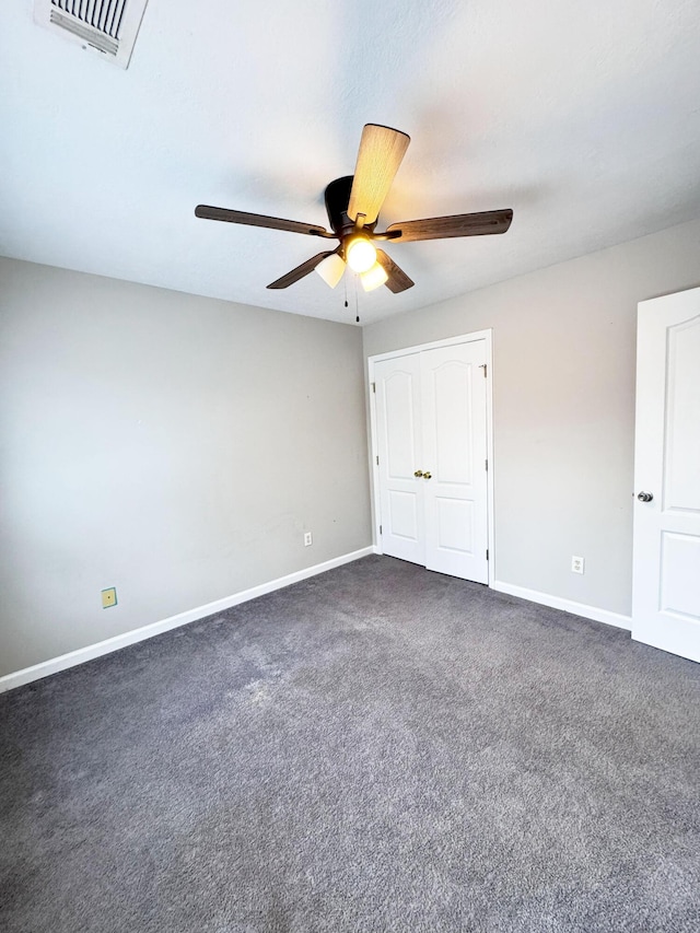 interior space with baseboards, visible vents, dark colored carpet, and ceiling fan