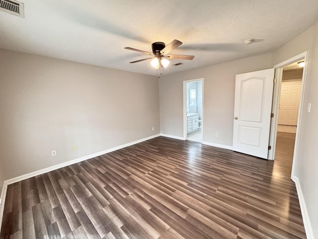 unfurnished room featuring visible vents, baseboards, dark wood-style floors, and a ceiling fan