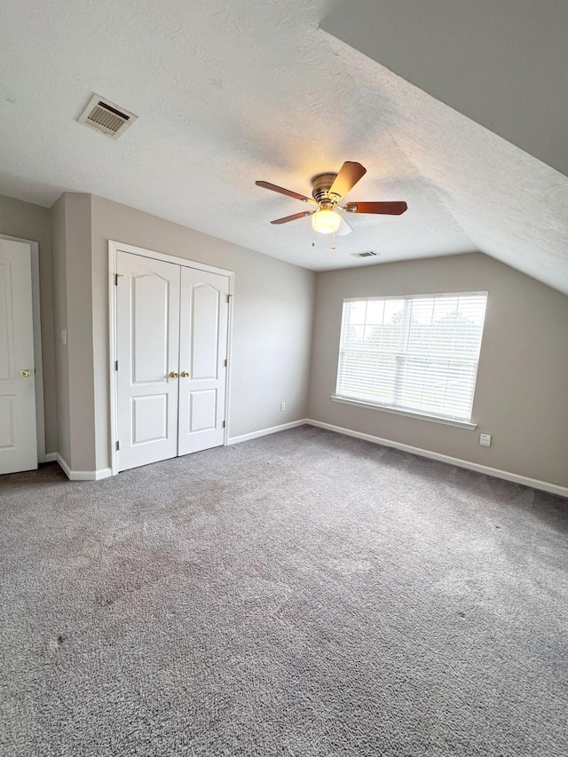 unfurnished bedroom with carpet flooring, visible vents, a closet, and a textured ceiling