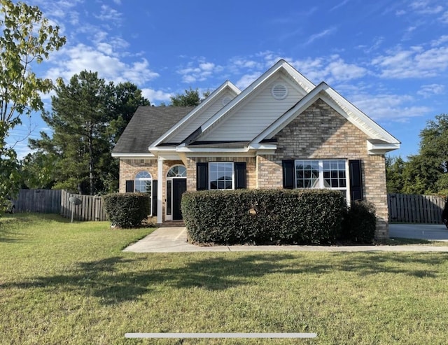 craftsman-style house with brick siding, a front yard, and fence