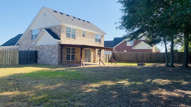 back of house featuring a yard, brick siding, and a fenced backyard