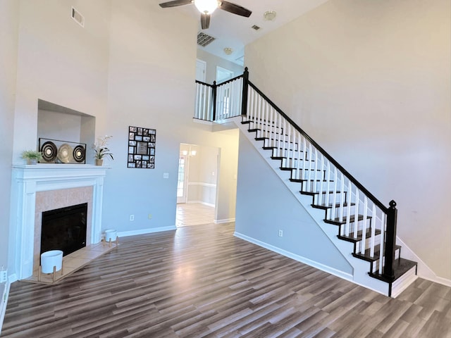 unfurnished living room with visible vents, baseboards, stairs, wood finished floors, and a ceiling fan