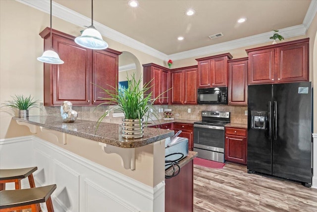 556 Ernestine Fls, Grovetown, GA 30813 - kitchen featuring black appliances, a peninsula, decorative light fixtures, a breakfast bar, and light wood finished floors