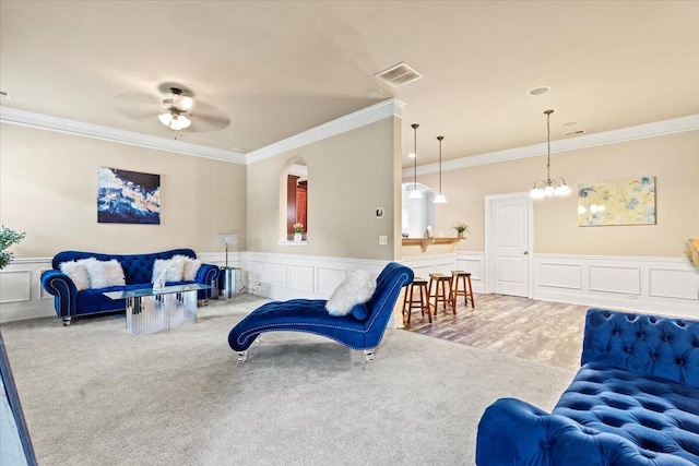 556 Ernestine Fls, Grovetown, GA 30813 - carpeted living room featuring ornamental molding, a ceiling fan, a decorative wall, arched walkways, and a chandelier