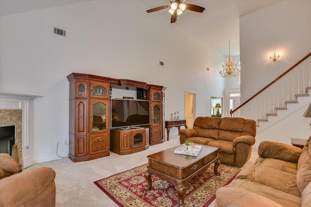 living room featuring light colored carpet, high vaulted ceiling, ceiling fan with notable chandelier, visible vents, and stairway