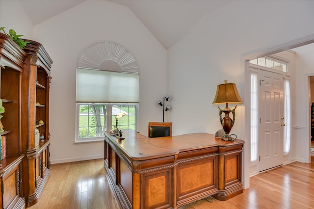 office featuring baseboards, light wood-style flooring, and lofted ceiling