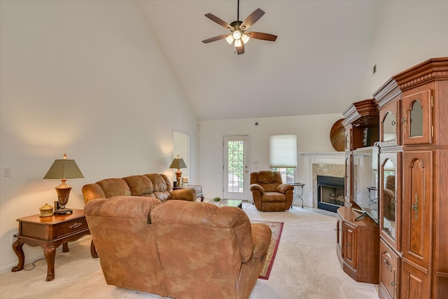 living area with high vaulted ceiling, light carpet, a ceiling fan, and a tile fireplace
