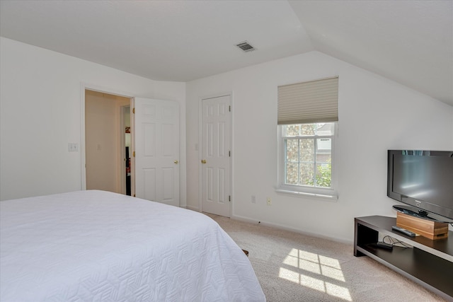 bedroom with light colored carpet, lofted ceiling, and visible vents
