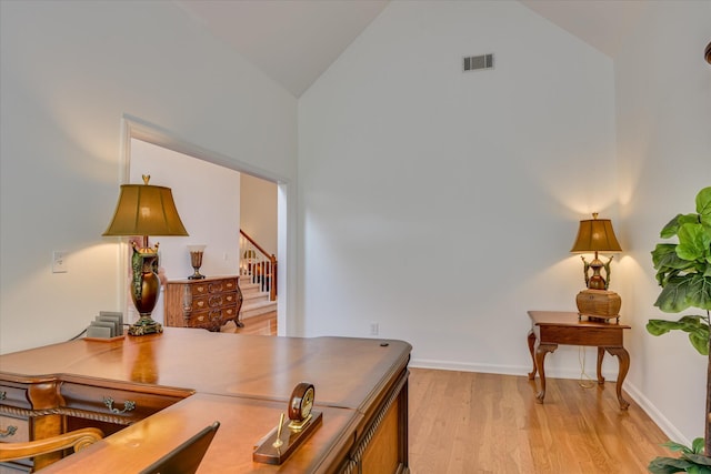 office space with visible vents, baseboards, high vaulted ceiling, and light wood-type flooring