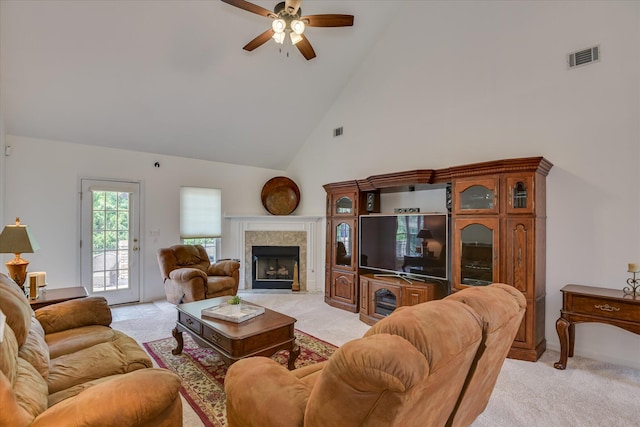 living area featuring a ceiling fan, visible vents, light colored carpet, a tile fireplace, and high vaulted ceiling