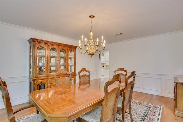 dining room with visible vents, ornamental molding, light wood finished floors, and a notable chandelier