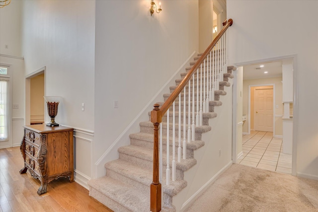 stairs featuring baseboards, a high ceiling, and a wealth of natural light