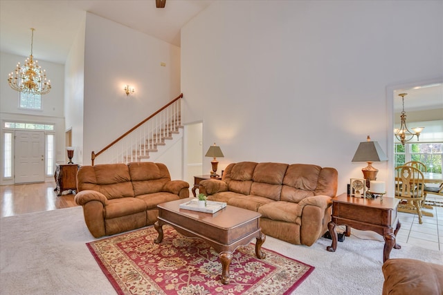 living room with an inviting chandelier, a high ceiling, carpet flooring, and stairs