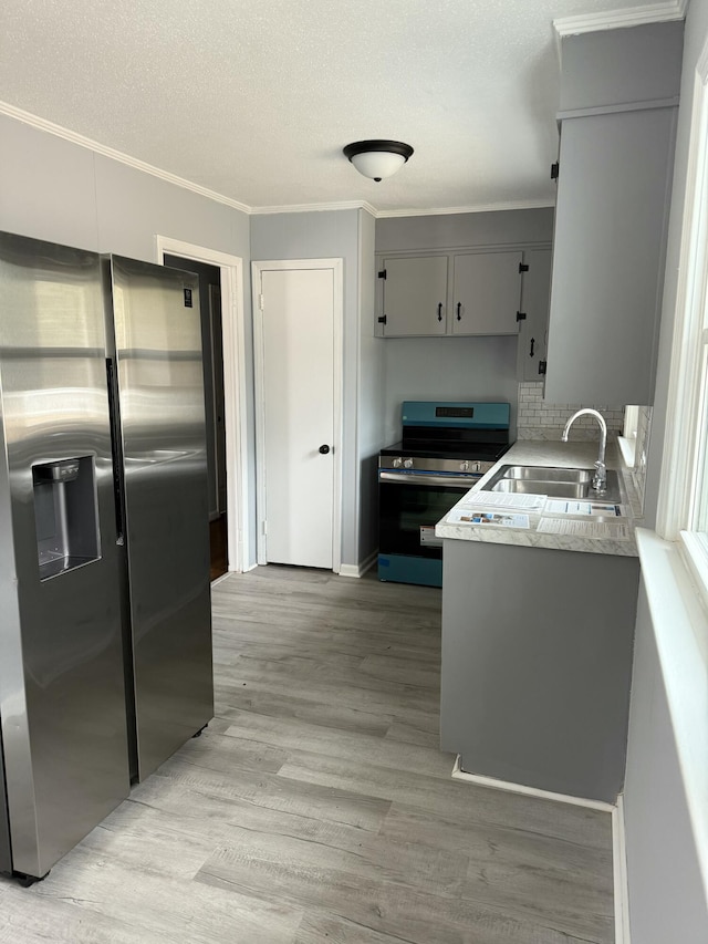 kitchen featuring appliances with stainless steel finishes, sink, gray cabinets, and light hardwood / wood-style flooring