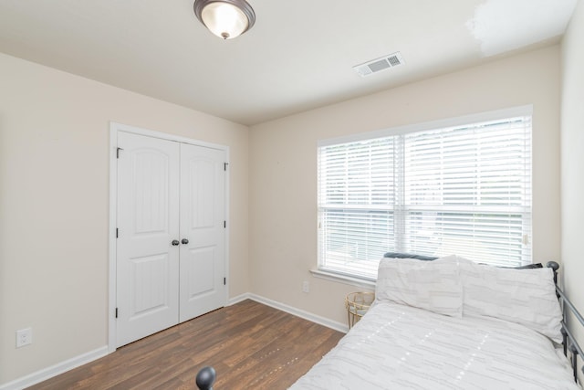 bedroom with dark wood-style flooring, baseboards, visible vents, and a closet