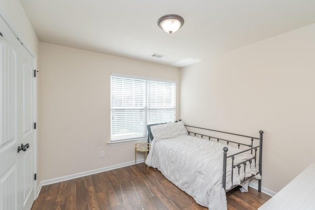 bedroom featuring baseboards, a closet, wood finished floors, and visible vents