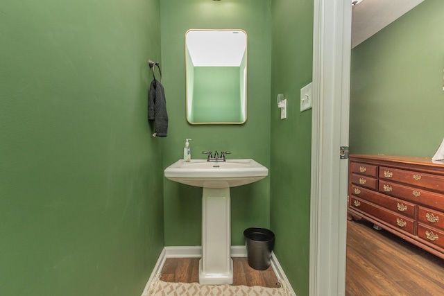 bathroom featuring baseboards, a sink, and wood finished floors