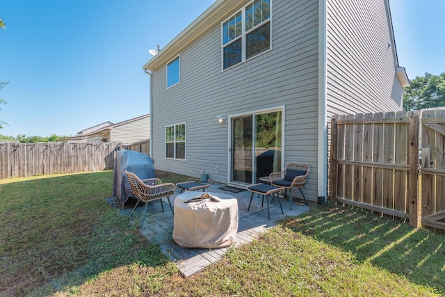 rear view of house featuring a yard, a patio, a fenced backyard, and an outdoor fire pit