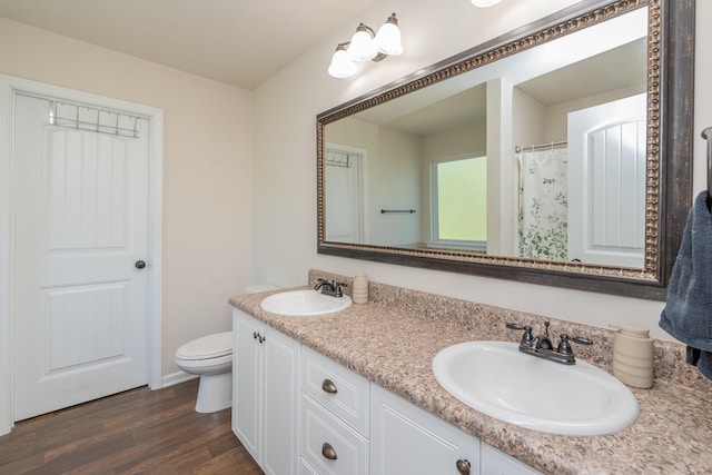 full bath featuring double vanity, a sink, wood finished floors, and toilet