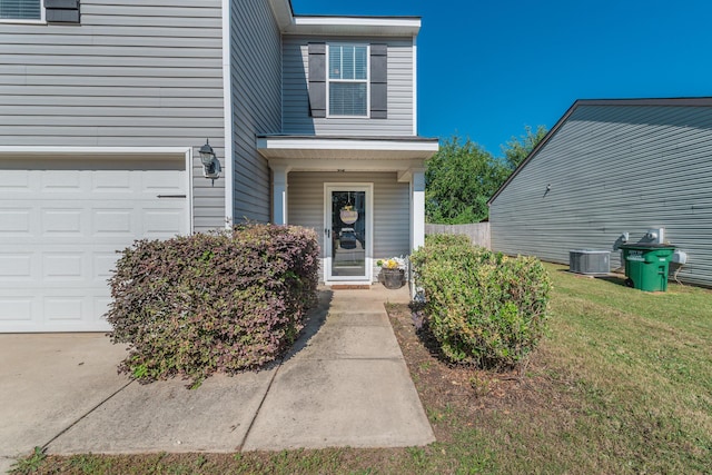 entrance to property featuring a lawn, central AC unit, and a garage