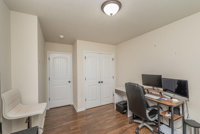 office area with dark wood-style flooring and baseboards
