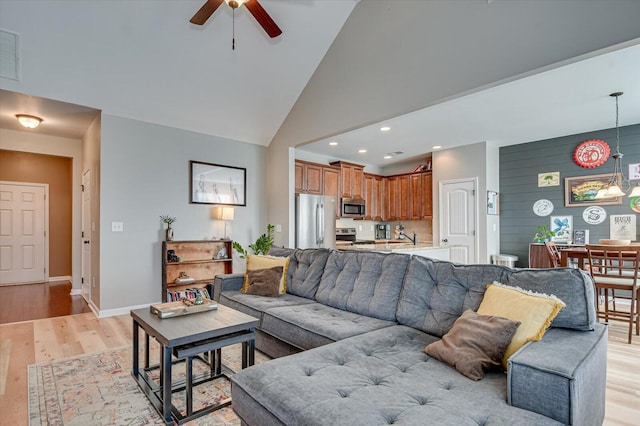 living room with a ceiling fan, baseboards, high vaulted ceiling, recessed lighting, and light wood-style floors