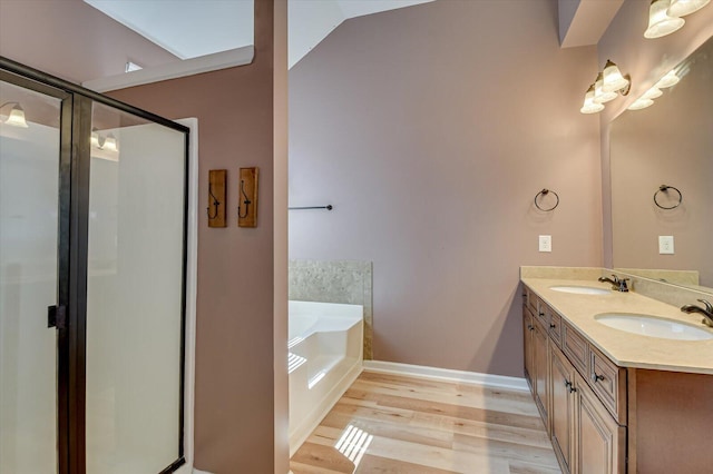 full bathroom featuring a stall shower, wood finished floors, a garden tub, and a sink