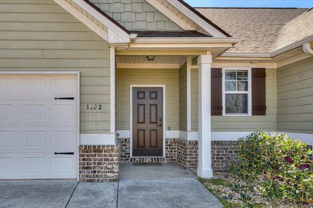 entrance to property with a garage and roof with shingles