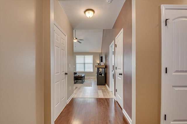 corridor featuring baseboards and hardwood / wood-style floors