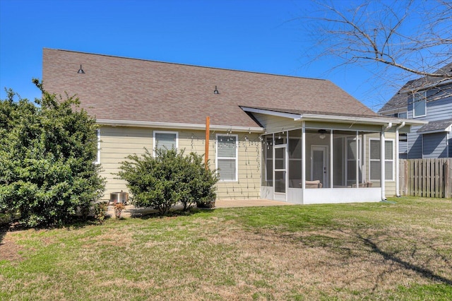 rear view of house with a yard, fence, a sunroom, and roof with shingles